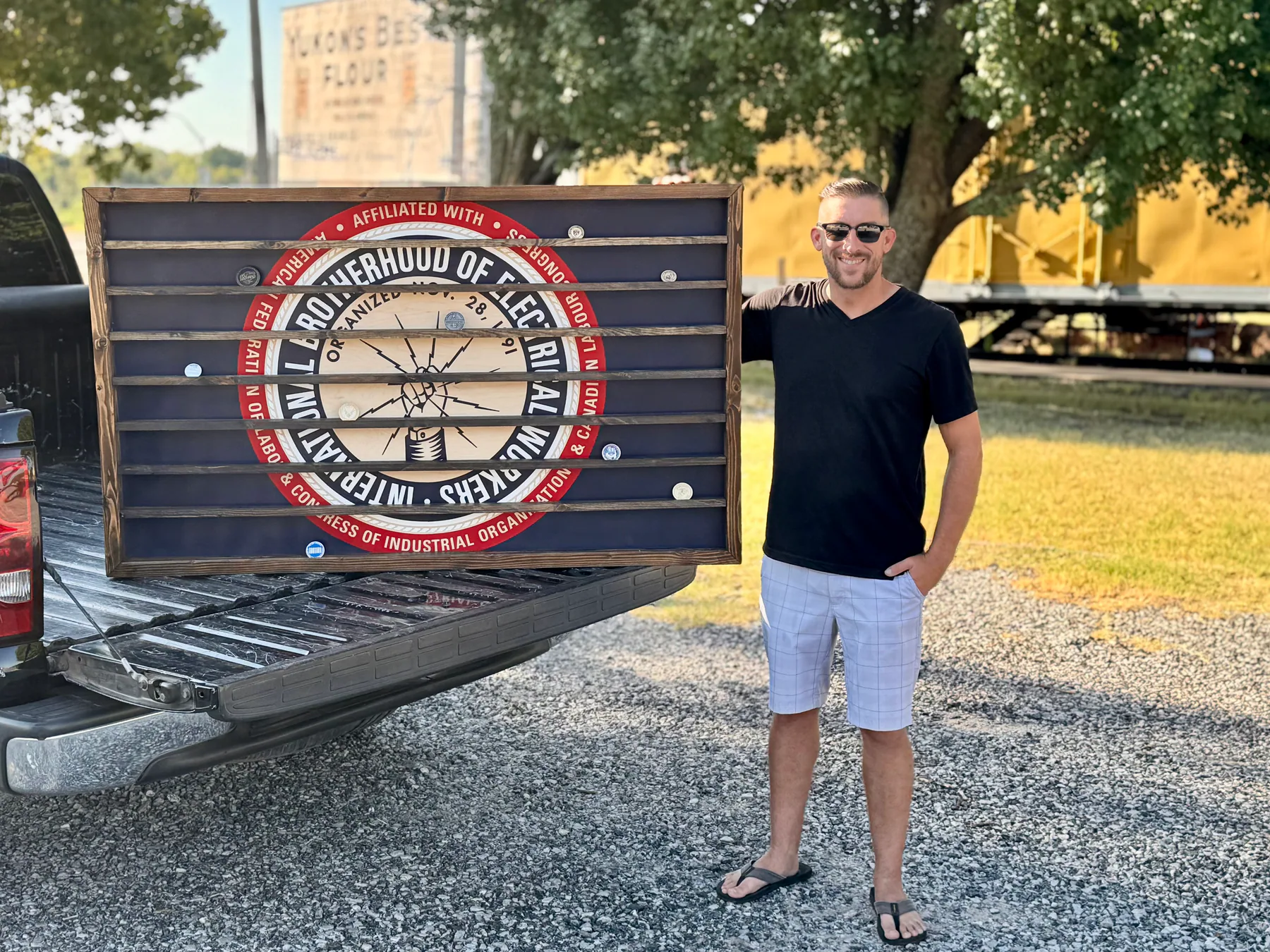 Jon Thetford of T6 Design Co. standing beside his five foot by three foot IBEW challenge coin display in Yukon, Oklahoma